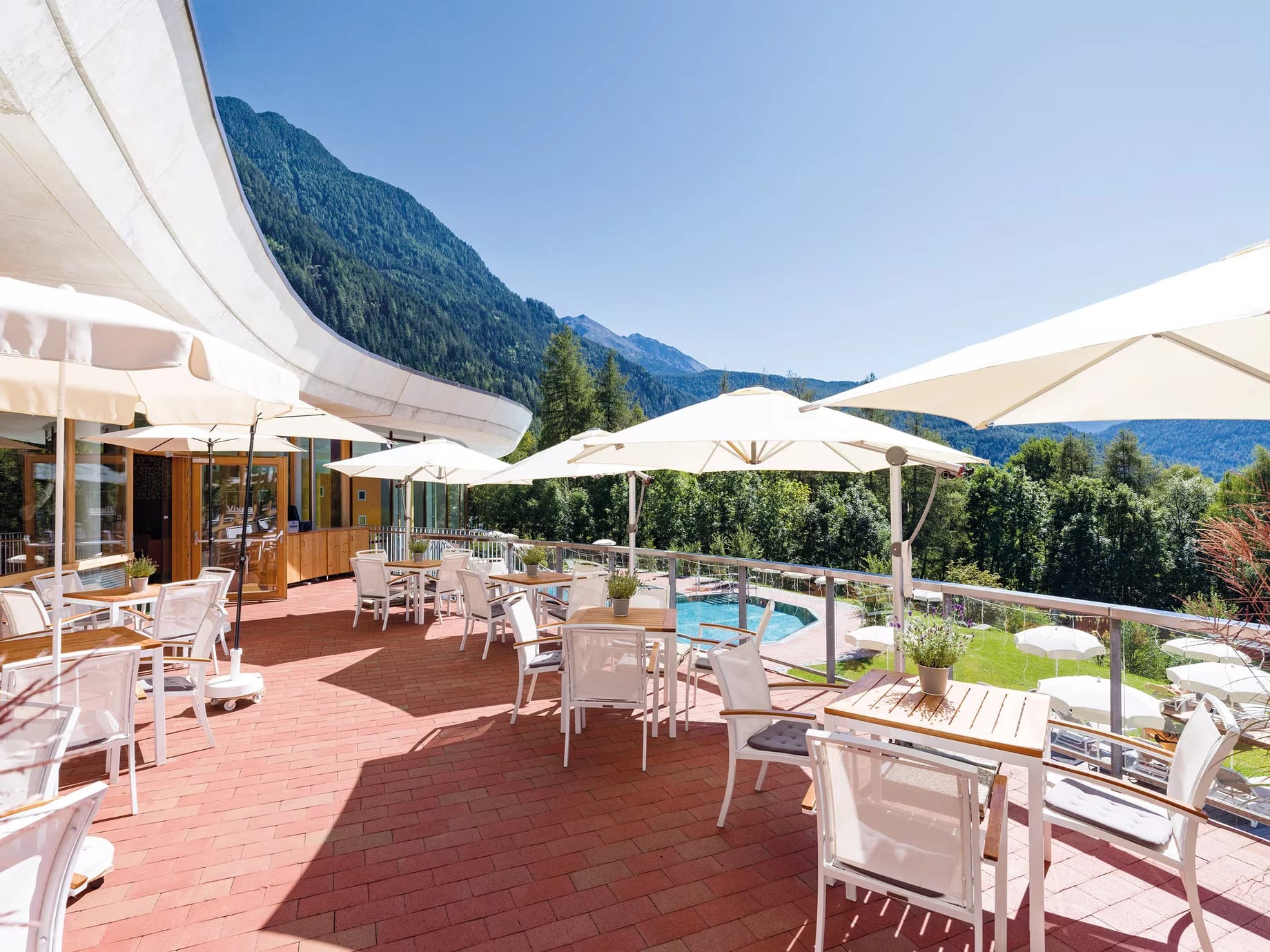 Sonnenterrasse mit Tischen und Sonnenschirmen und Bergblick