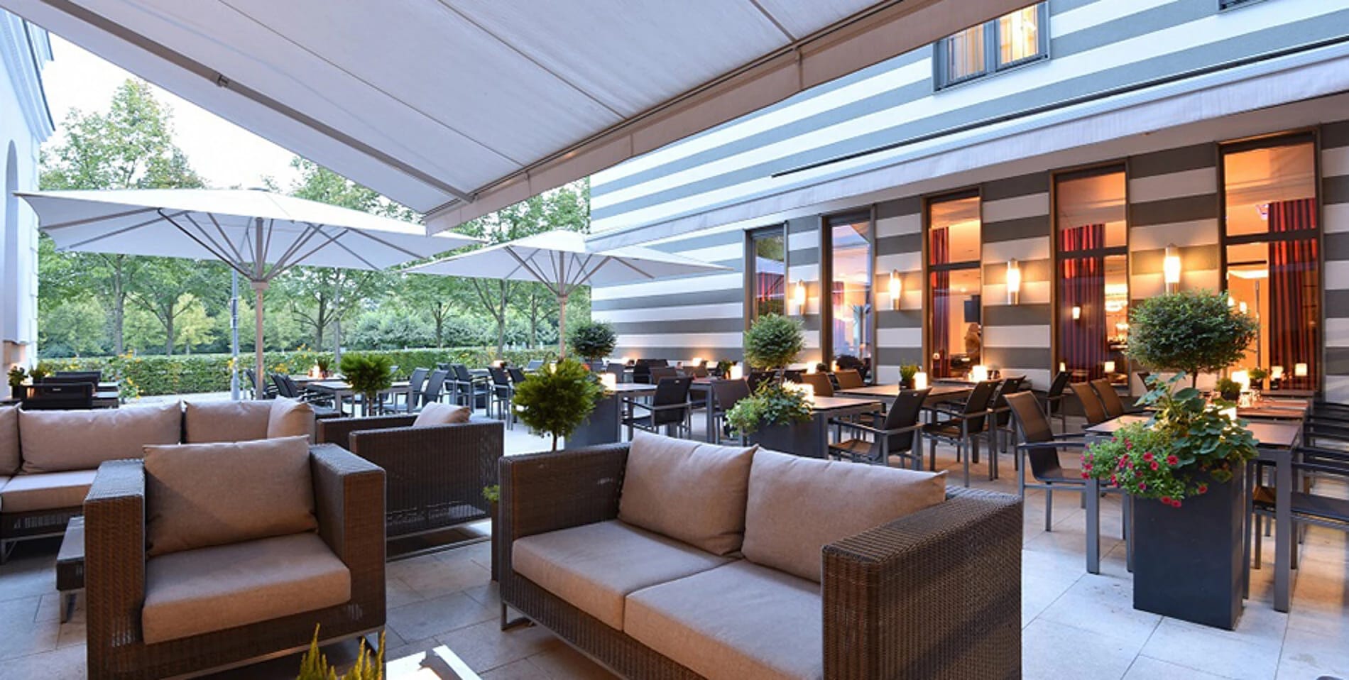 Sonnenterrasse mit Sonnenschirmen und Loungemöbeln im Grünen