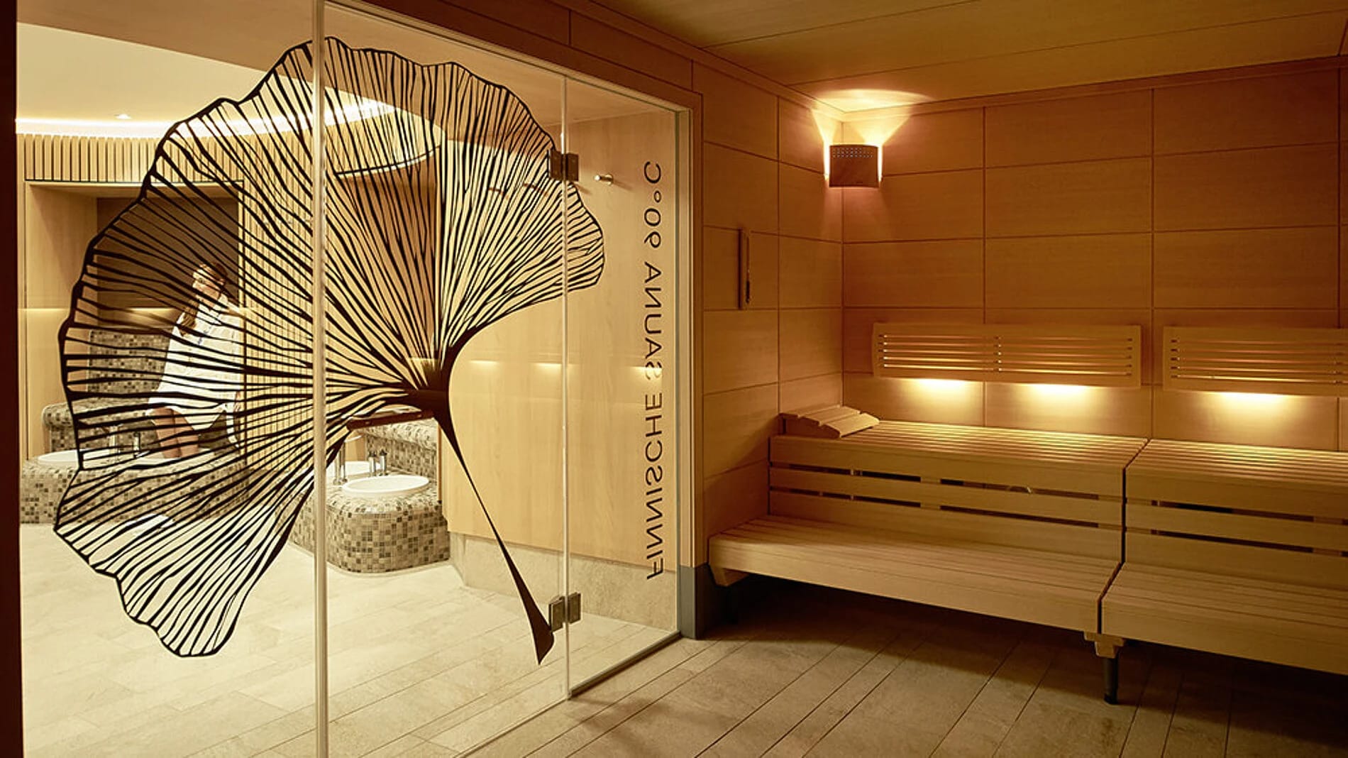 Finnische Sauna mit Holzbänken und Glastür mit Ginkgo-Motiv