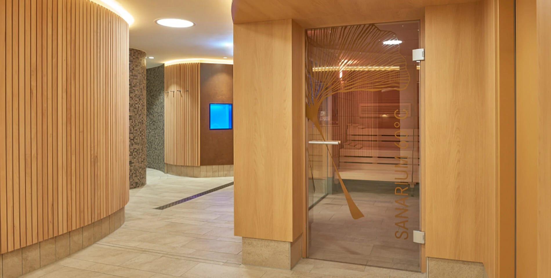 Wellnessbereich mit holzvertäfeltem Gang und Sauna hinter Glas