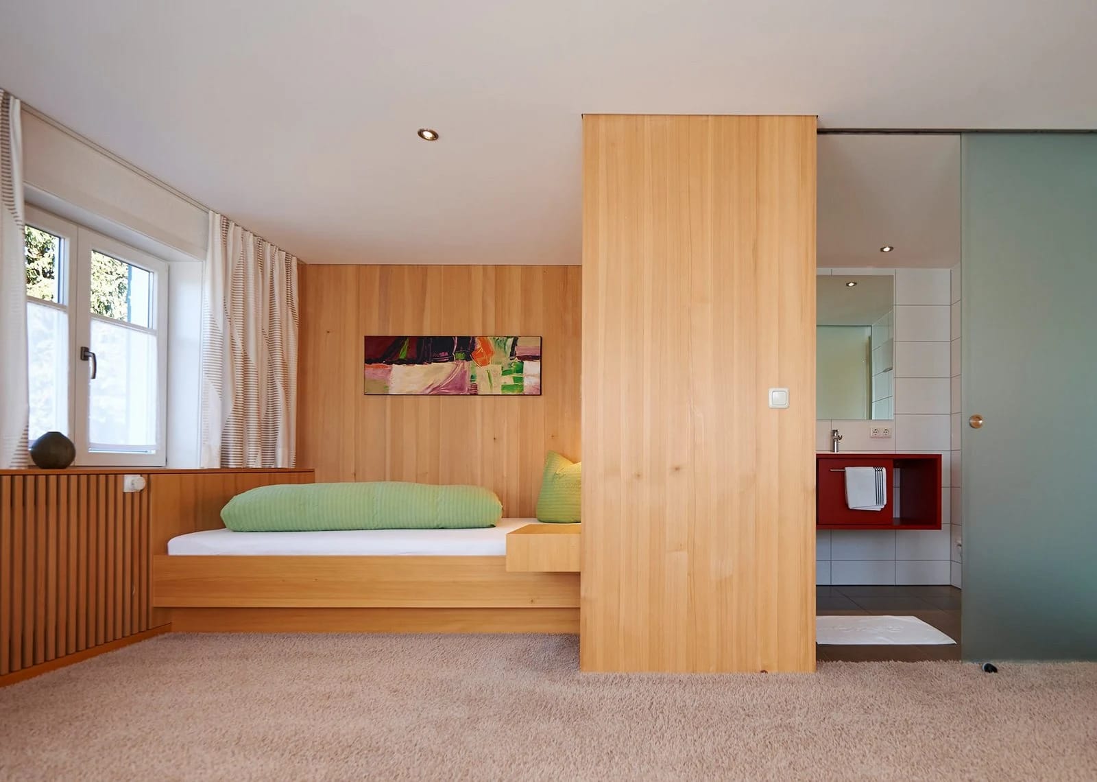 Zimmer mit Doppelbett aus Holz, Holzdecke, Schreibtisch und Sessel am Fenster