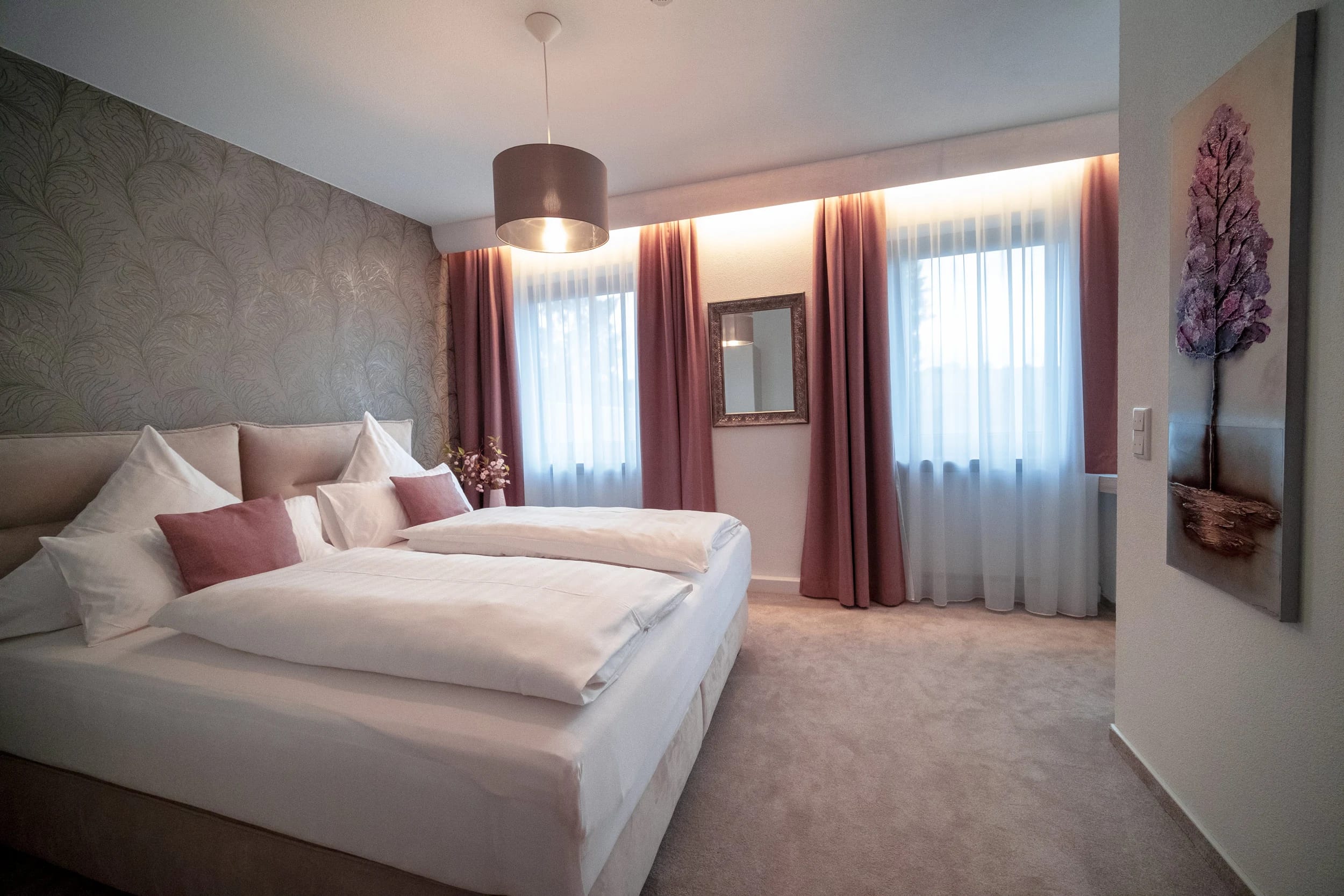 Doppelzimmer mit zusammengestellten Betten, altrosa Vorhängen und gemusterter Wand