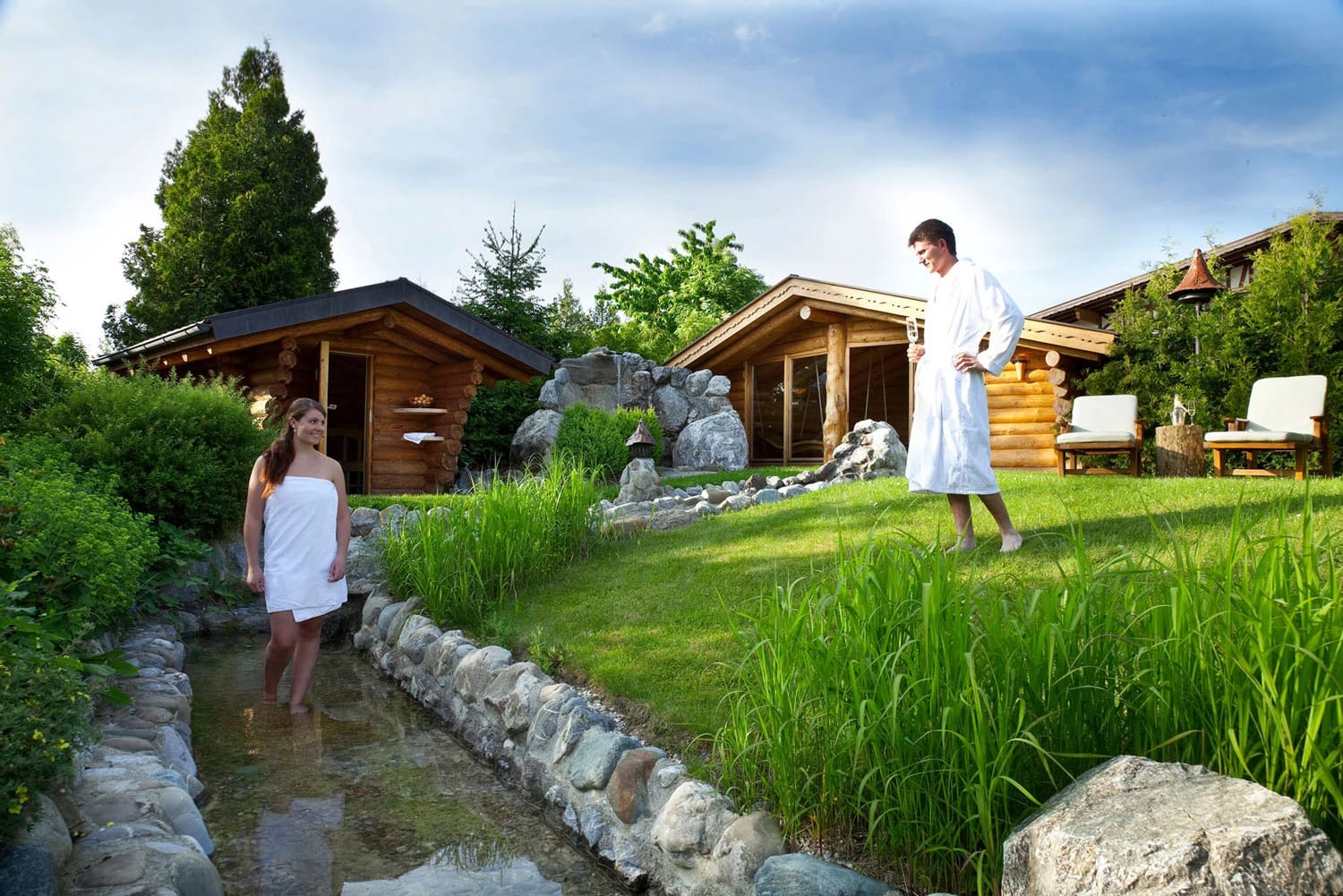 Sauna-Garten mit Holzsaunahütten und naturnahem Wasserlauf