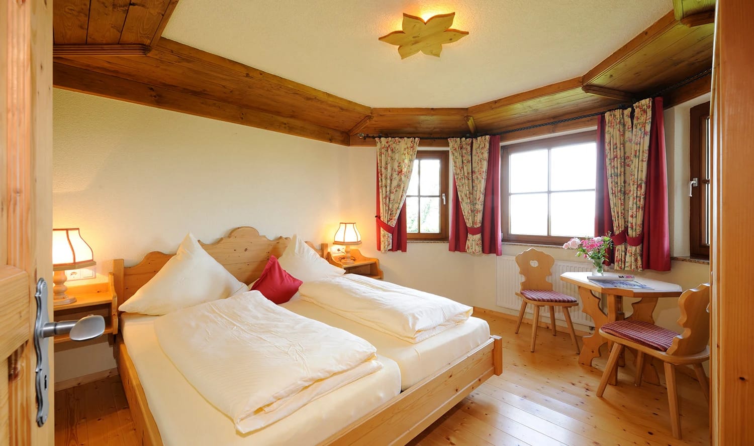 Doppelzimmer mit Holzbalkendecke und Sitzecke am Fenster