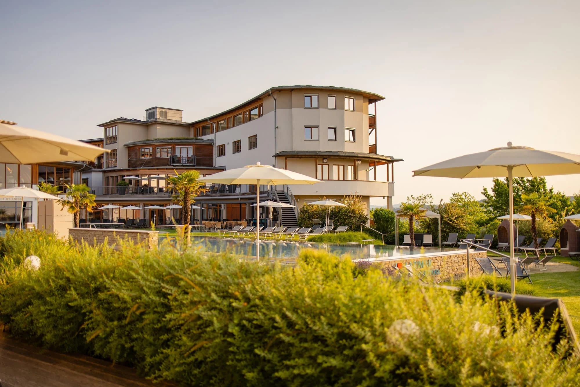Außenansicht des Hotels mit Poolterrasse und Sonnenschirmen im Sommer