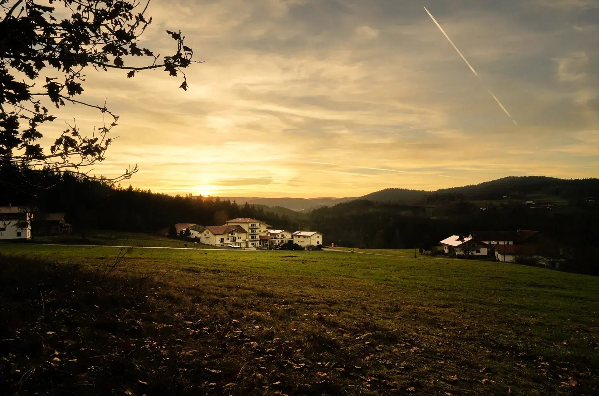 Das Hotel in der hügeligen Landschaft des Bayerischen Waldes im Licht der Abendsonne
