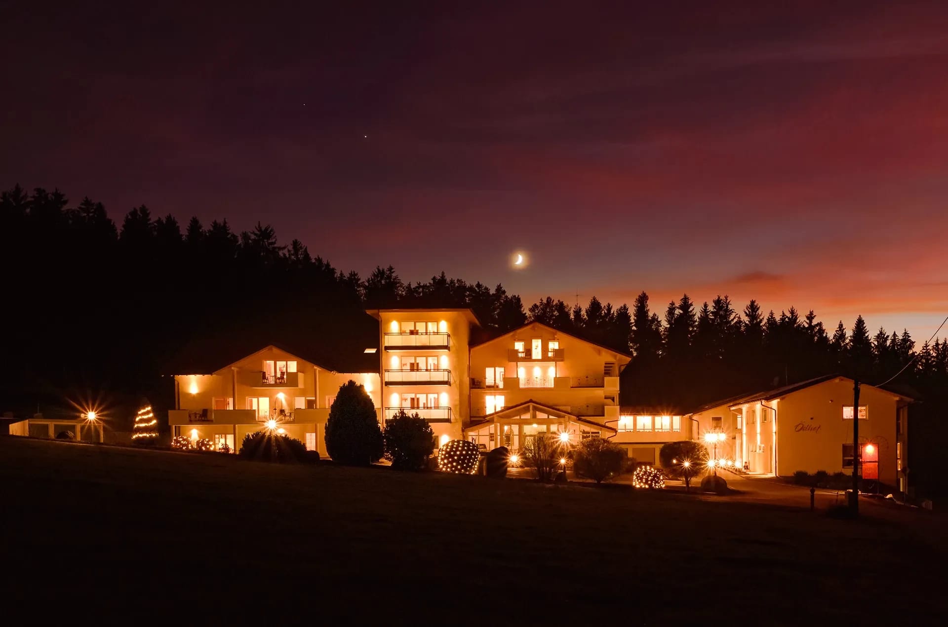 Das beleuchtete Hotelgebäude bei Nacht mit angestrahlter Fassade vor dem Abendhimmel