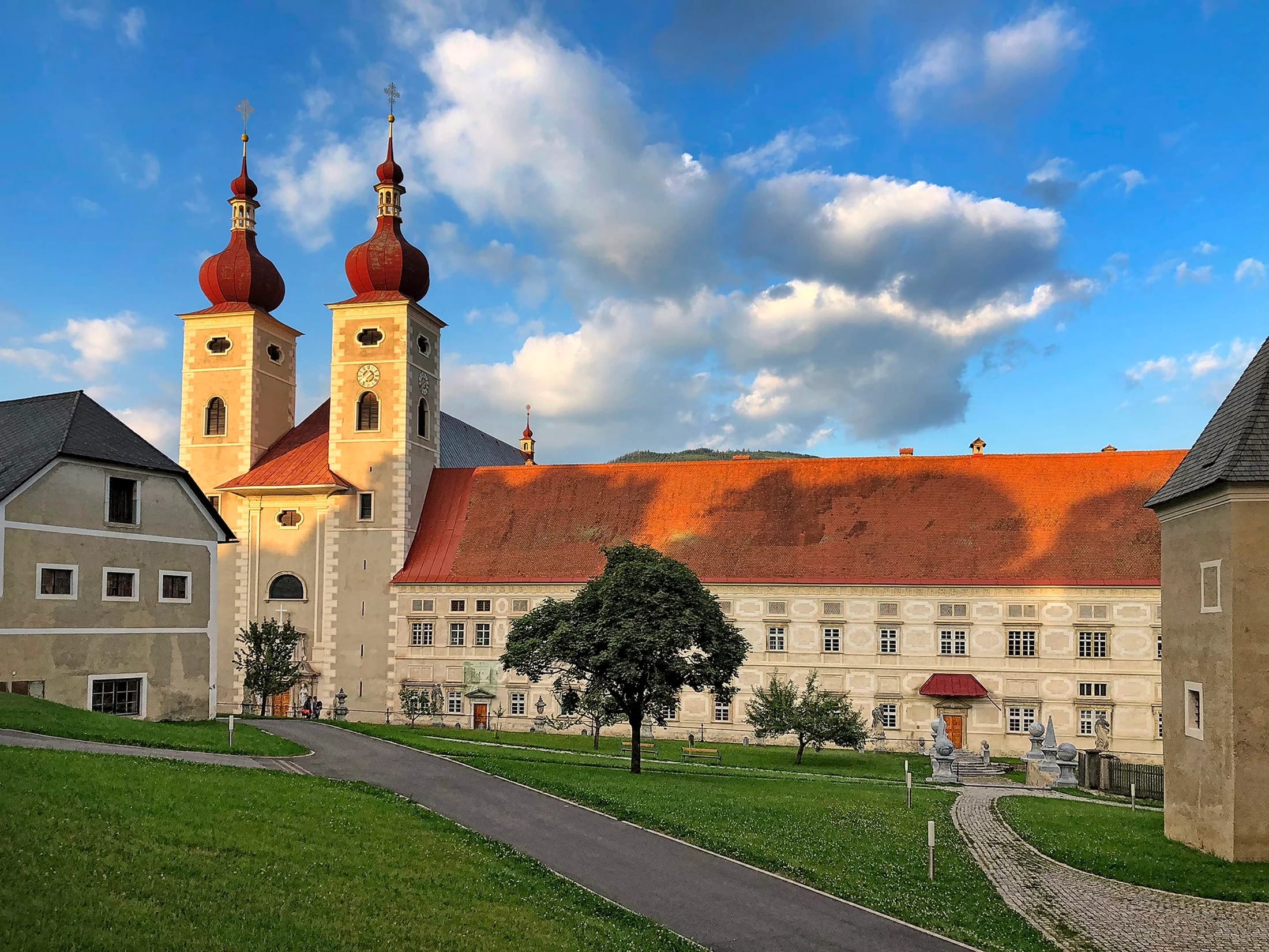 Stiftskirche mit zwei Zwiebeltürmen und angrenzendem Klostertrakt im Abendlicht