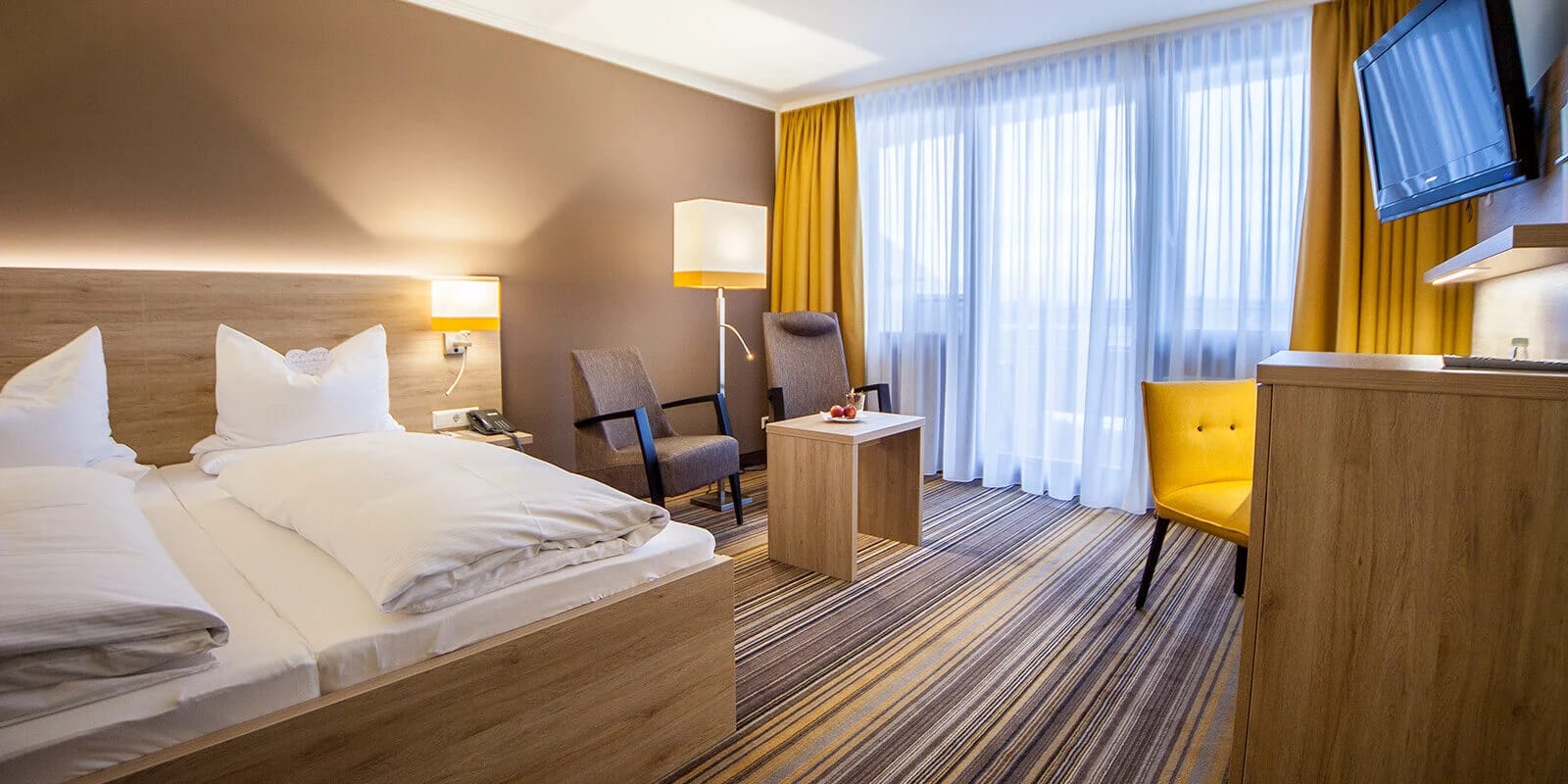 Doppelzimmer mit Doppelbett, Sitzecke und bodentiefem Fenster