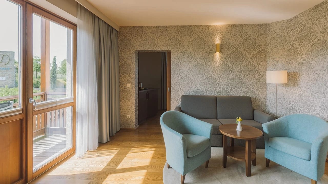 Wohnbereich einer Suite mit Sofa, Sesseln und Balkontür