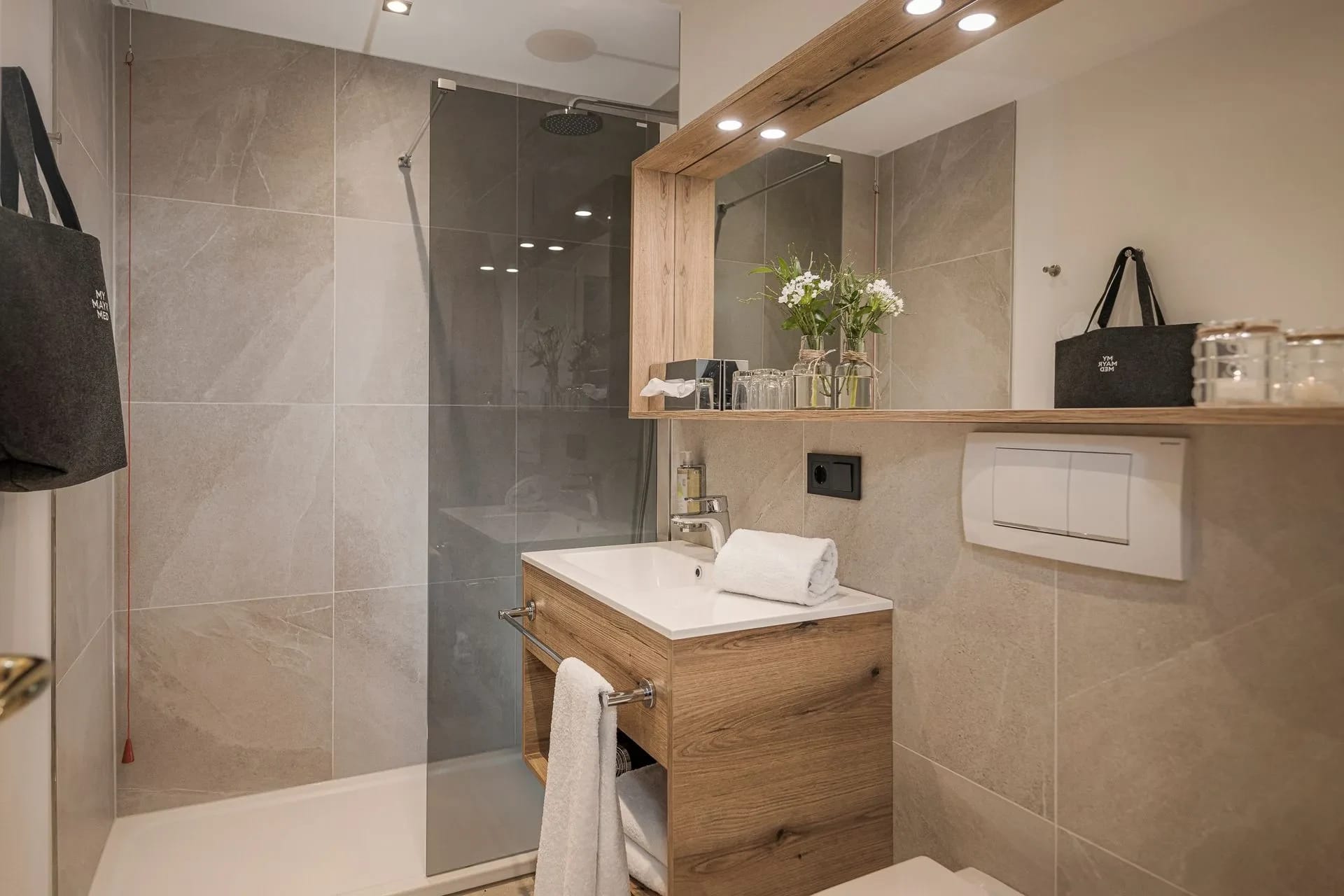 Badezimmer mit ebenerdiger Glasdusche, Holzwaschtisch und großem Spiegel