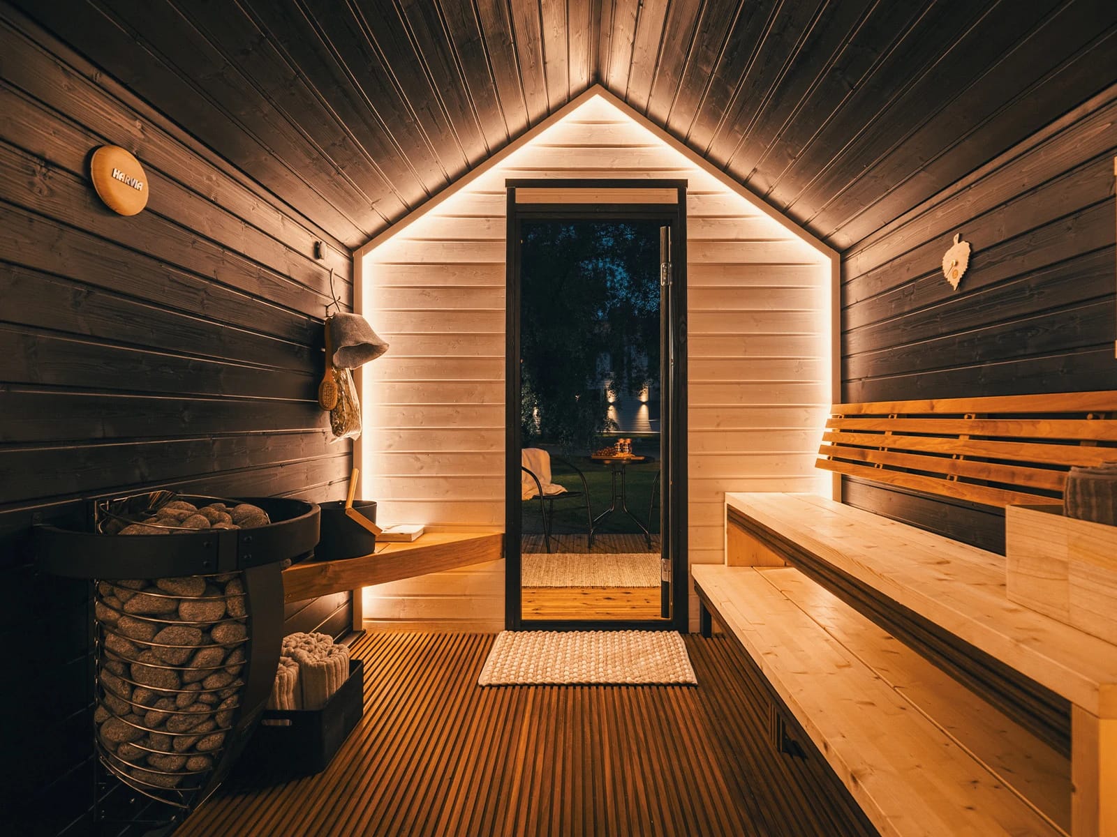 Sauna mit hellen Holzbänken, Saunaofen und Glastür ins Freie