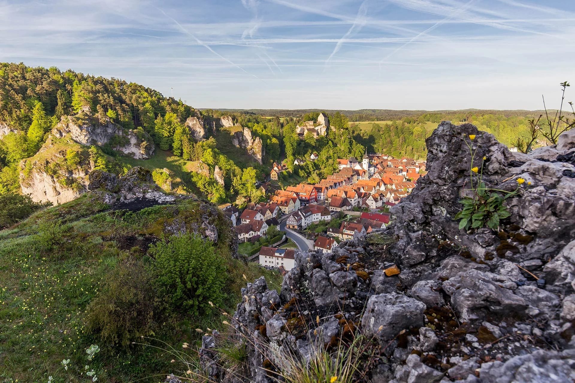 Blick von den Felsen über den Ort Pottenstein mit roten Dächern, Burg und bewaldeten Hängen