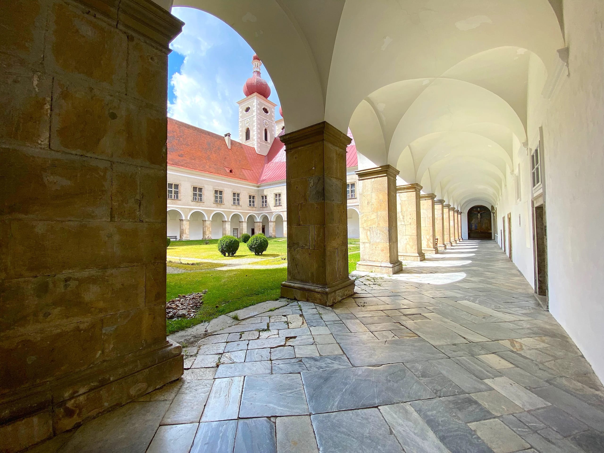 Gewölbter Arkadengang im Innenhof mit Blick durch den Bogen auf den Kirchturm
