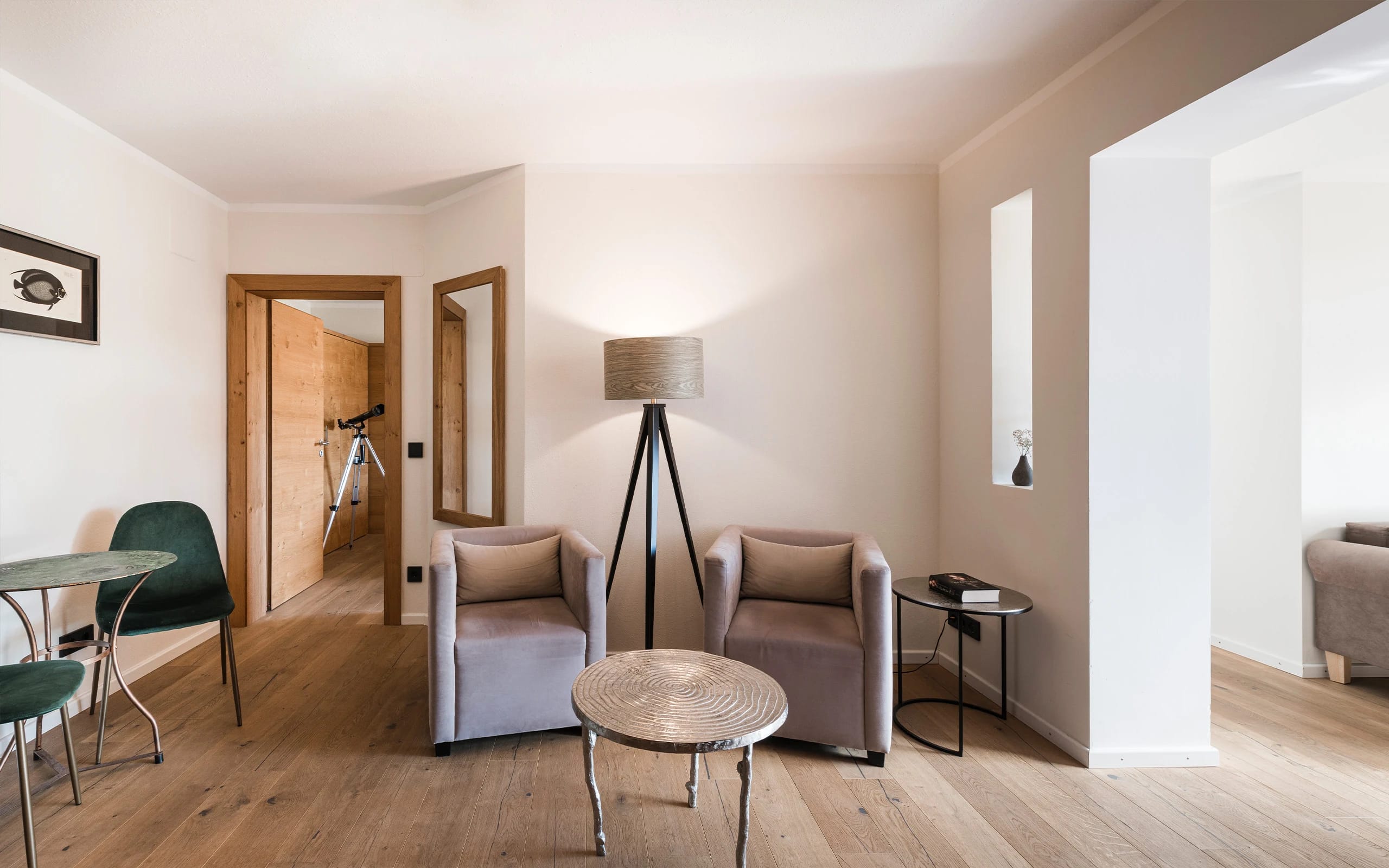 Wohnbereich einer Suite mit zwei Sesseln, Stehlampe und offener Tür zum Schlafzimmer