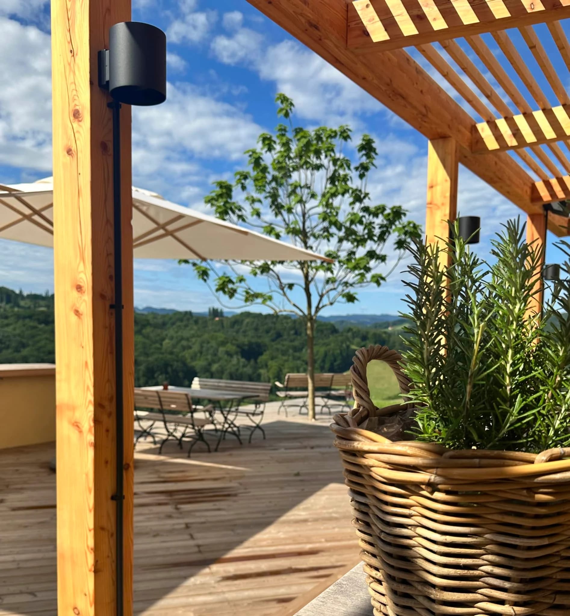 Sonnige Holzterrasse mit Sonnenschirmen und Blick über die Landschaft