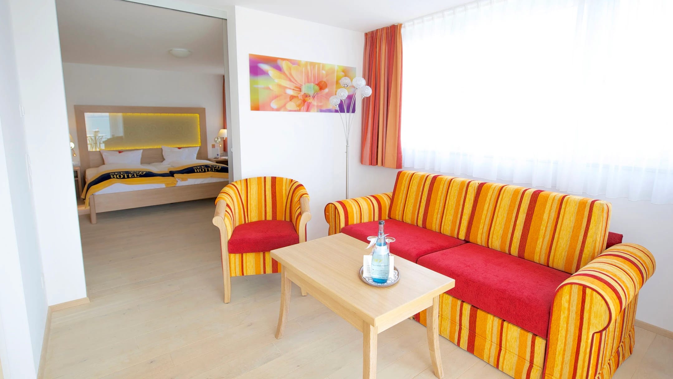 Wohnbereich einer Suite mit Sofa und Sesseln, dahinter der Schlafbereich